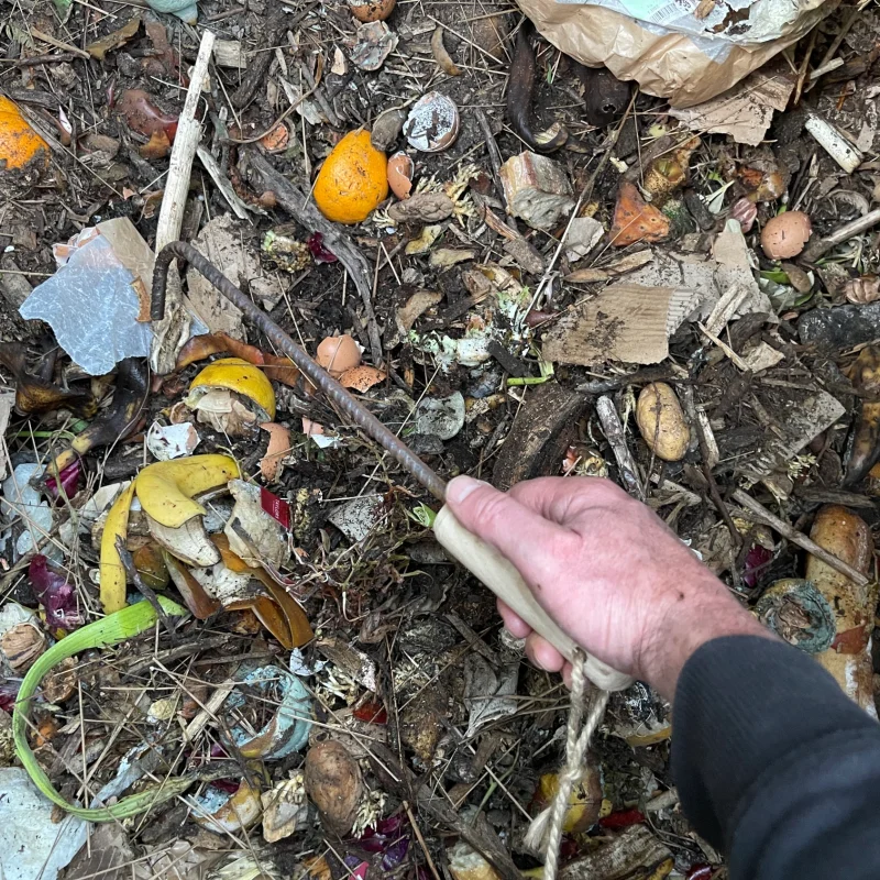 Le bac d'apport de l'air de compostage collectif avec le crochet à compost en utilisation.